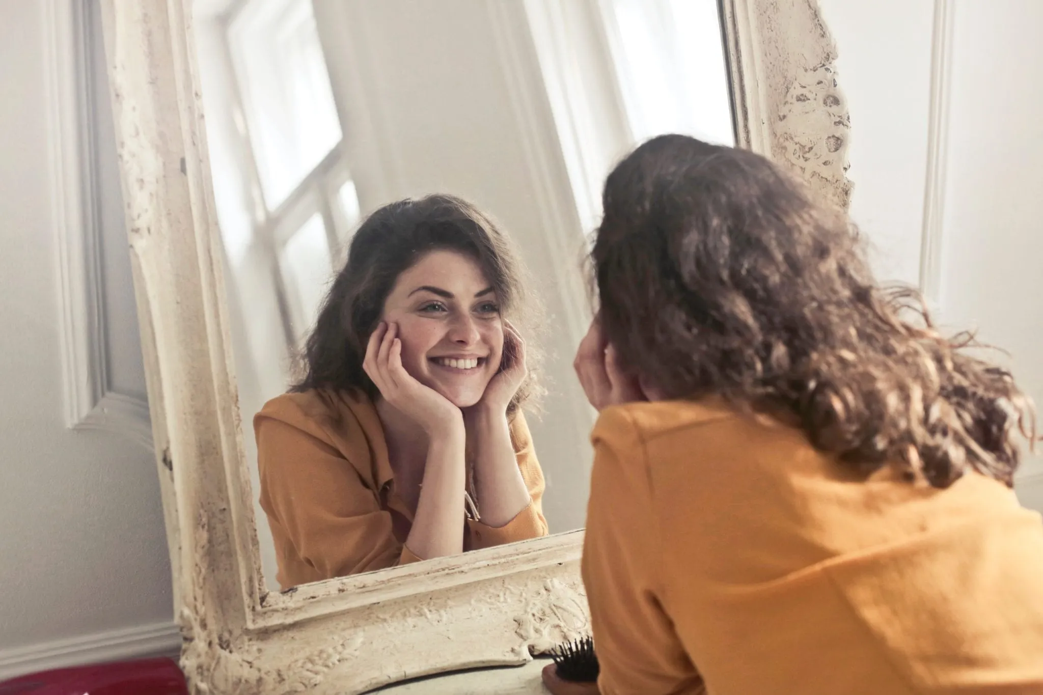 A woman looks at her reflection in a mirror.