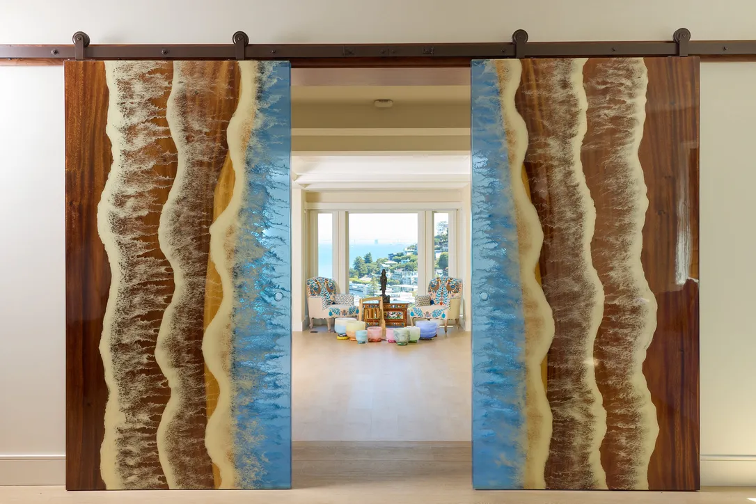 Carved walnut and resin sliding doors, drawn closer, framing the ballroom and the bay beyond.