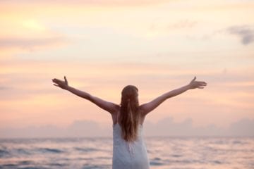 girl with arms open freely at the beach